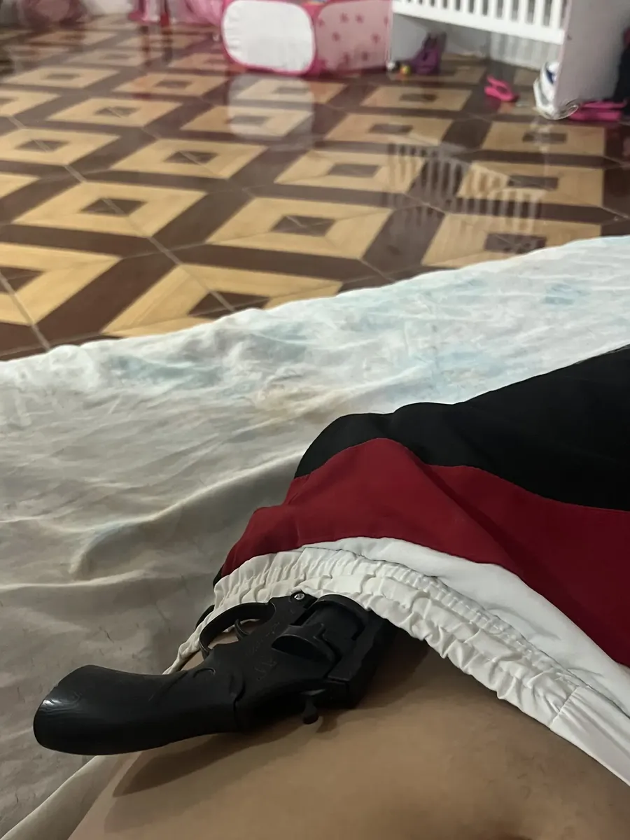 Revólver de brinquedo colocado sobre a cama depois de brincadeira em casa.